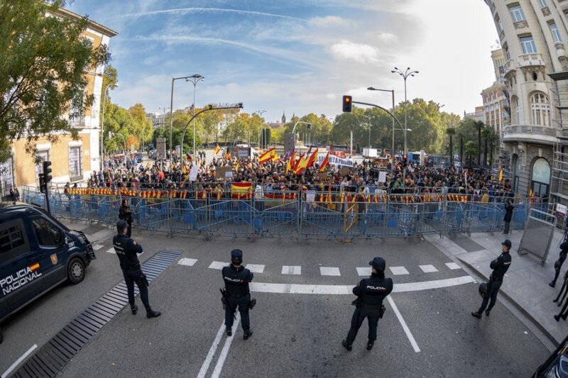 Varios policías desplegados ante un grupo de opositores a la investidura del líder socialista Pedro Sánchez que se manifiestan en los alrededores del Congreso de Diputados mientras el presidente del Gobierno en funciones, Pedro Sánchez, se dirige a la Cámara en el primer día de su debate de investidura para exponer su nuevo programa de Gobierno y pedir la confianza a la Cámara para revalidar su mandato en la Moncloa, este miércoles. EFE/Fernando Villar