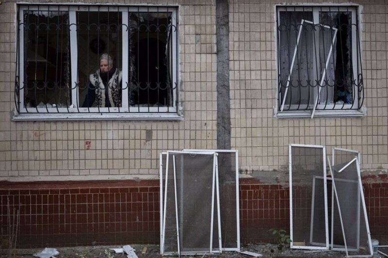 Una mujer mira por la ventana de un edificio dañado a causa de un ataque del Ejército de Rusia contra la capital de Ucrania, Kiev (archivo). Imagen: Oleksii Chumachenko/SOPA Images / DPA