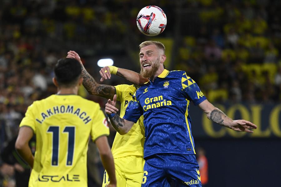 VILLARREAL (CSTELLÓN), 30/09/2024.- El delantero escocés de Las Palmas Oliver McBurnie (d) salta por el balón con Kiko Femenía (c), del Villarreal, durante el partido de la jornada 8 de LaLiga en Primera División que Villarreal CF y UD Las Palmas disputan este lunes en el estadio de La Cerámica. EFE/Andreu Esteban