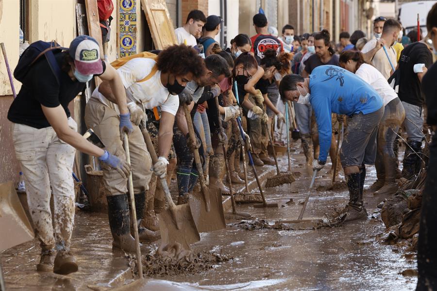 Varias personas retiran el lodo acumulado en una calle de la localidad valenciana de Paiporta. Imagen EFE