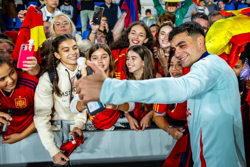 Pedri sacándose fotos junto a la afición en el entrenamiento solidario del Heliodoro Rodríguez López / RFEF