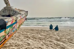 Dos hombres cerca de una embarcación de madera conocida como piragua, utilizada tradicionalmente para la pesca en Mauritania y África Occidental, en una playa de Nuakchot, Mauritania, el 28 de junio de 2022. Las piraguas han sido utilizadas con frecuencia por personas migrantes que intentan cruzar el océano Atlántico para llegar a las islas Canarias, en España. © 2022 Lauren Seibert/Human Rights Watch