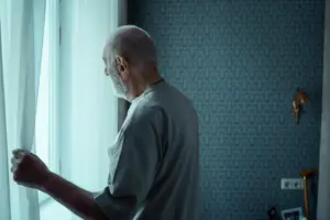 Imagen de archivo de una persona mayor mirando a través de una ventana