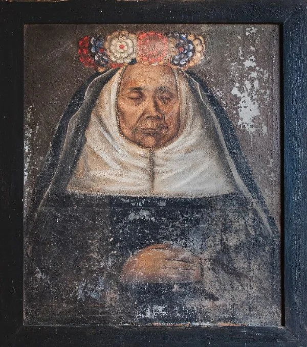 Retrato mortuorio de religiosa. Lleva corona de flores en la cabeza y las manos cruzadas sobre el pecho.