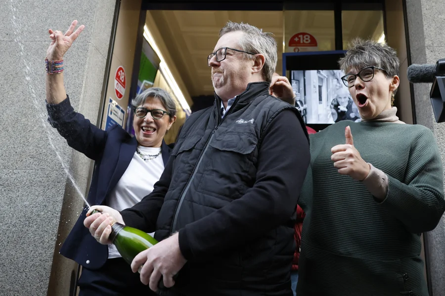 Varias personas celebran a las puertas de la administración de loterías del número 10 de la calle Barquillo, en Madrid, donde se ha vendido íntegramente el 70.048, el segundo premio del Sorteo Extraordinario de la Lotería de Navidad. EFE/Mariscal