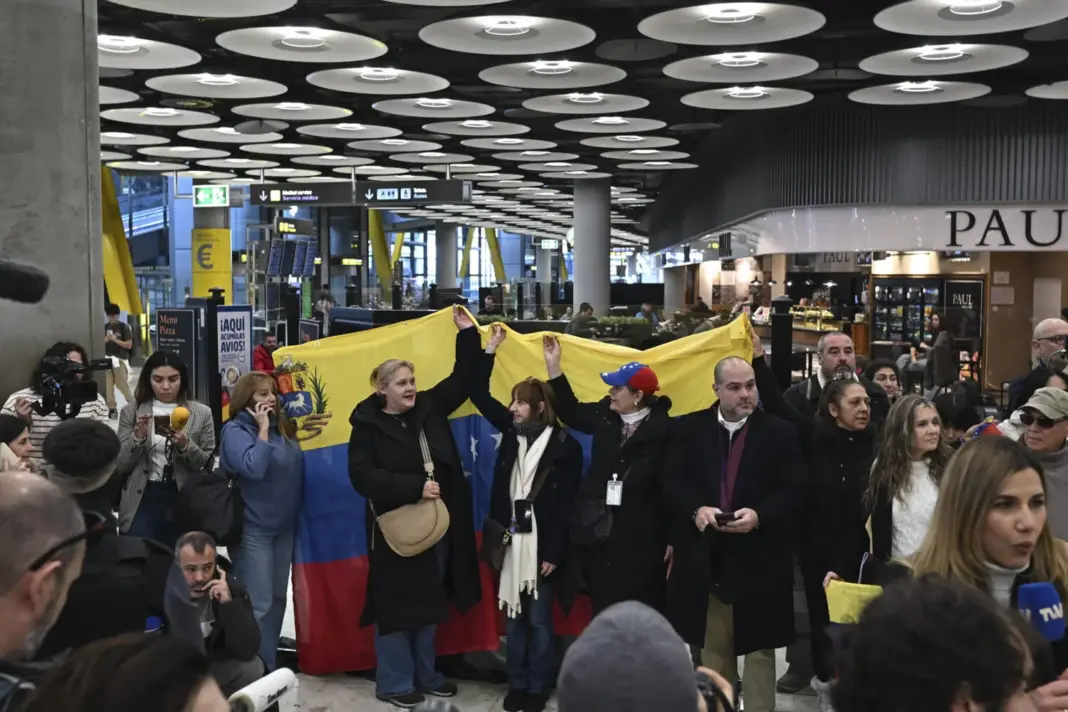 Un grupo de personas sostiene una bandera de Venezuela en el Aeropuerto Adolfo Suárez Madrid Barajas, este viernes. Los cinco presos españoles liberados en Venezuela llegaron a Madrid este viernes en un vuelo procedente de Bogotá, según confirmó el ministro de Asuntos Exteriores, José Manuel Albares, en un mensaje en la red social X. EFE/Fernando Villar