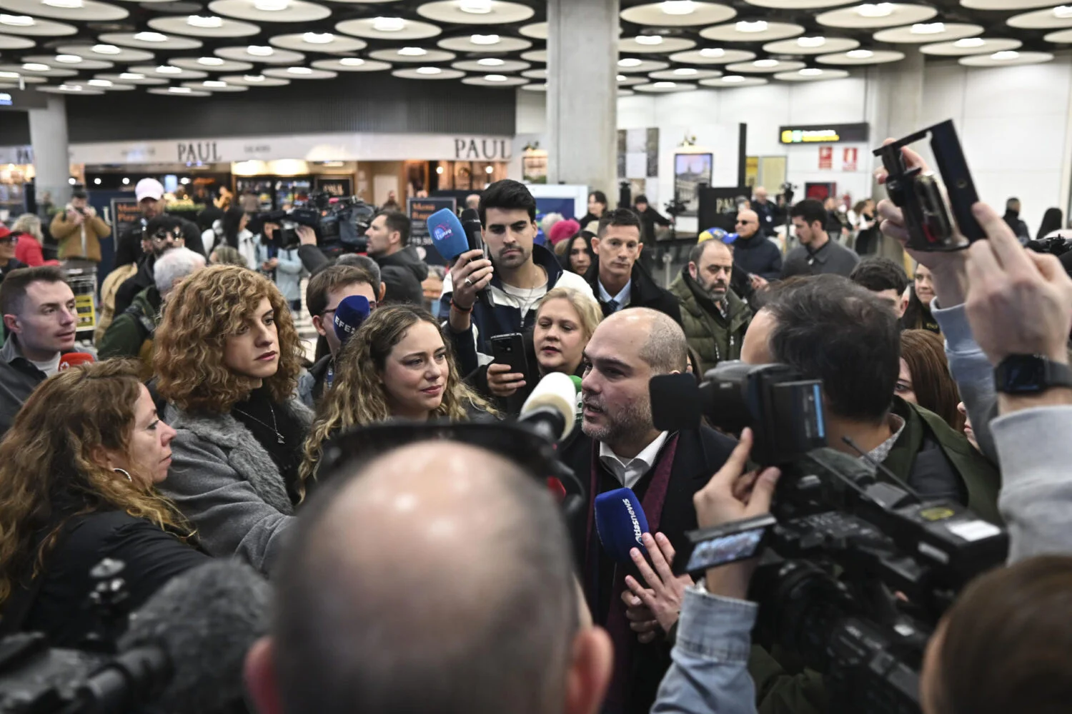 El portavoz de Refugiados Sin Fronteras, Sergio Contreras (c), se dirige a medios de comunicación en el Aeropuerto Adolfo Suárez Madrid Barajas, este viernes. Los cinco presos españoles liberados en Venezuela llegaron a Madrid este viernes en un vuelo procedente de Bogotá, según confirmó el ministro de Asuntos Exteriores, José Manuel Albares, en un mensaje en la red social X. EFE/Fernando Villar