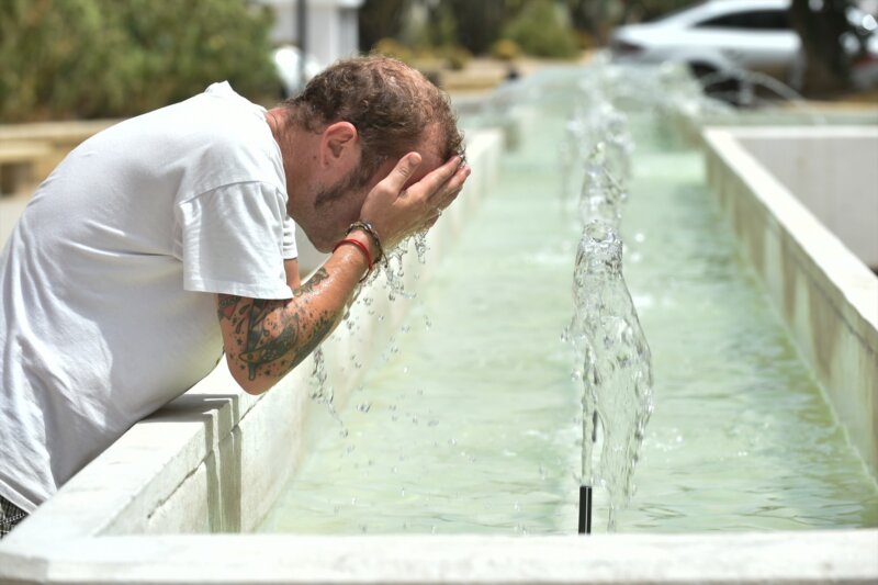 Un hombre se refresca en una fuente