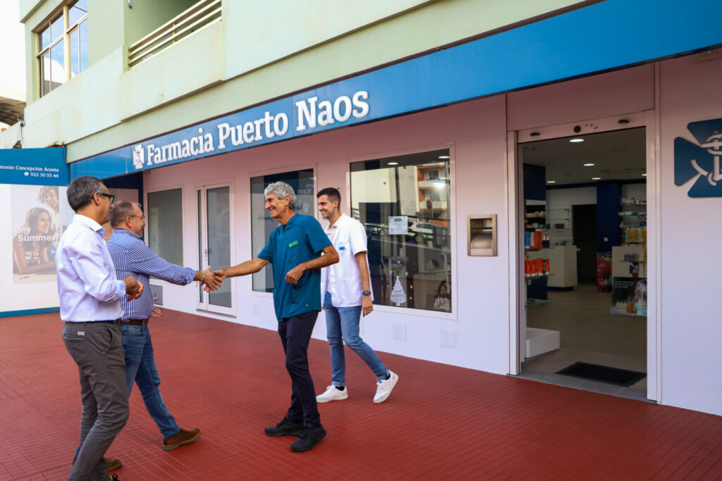 el presidente del Cabildo de La Palma, Sergio Rodríguez (2i), y el alcalde de Los Llanos de Aridane, Javier Llamas (i), saludan al propietario de la farmacia en la apertura del establecimiento. EFE / Luis G Morera